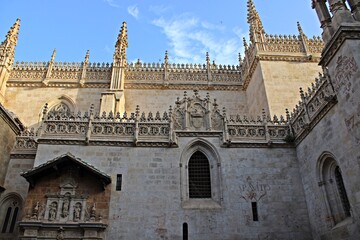 Fototapeta premium Gothic spires and ornate stonework of Granada Cathedral in Spain. Featuring ornate spires, carved religious motifs, medieval windows and historic heraldic symbols