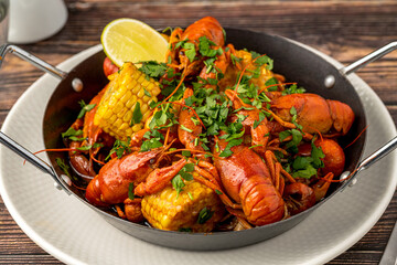 Cooked crayfish with corn and herbs in a serving pan