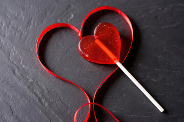 A simple red heart shape, a powerful symbol of love and romance, is isolated on a stark black background with lolipop
