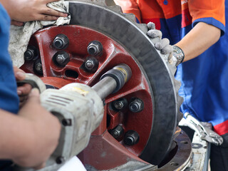 Two mechanics work together to repair a differential gear with air impact, demonstrating skilled...