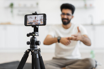 Young adult man recording video in bright room, demonstrating smartwatch capabilities for athletes