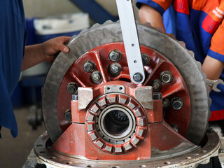 ​A mechanic uses a large torque wrench to tighten bolts on a differential crown gear, showcasing...