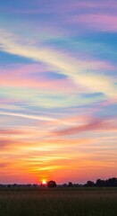 Fototapeta premium Vibrant Sunset Over Rural Landscape with Colorful Sky and Silhouetted Horizon.