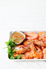Grilled shrimps with spicy sauce in a white tray.