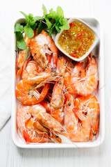 Grilled shrimps with spicy sauce in a white tray.