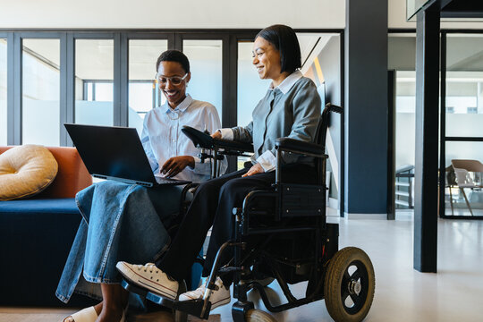 Professional workplace interaction between colleagues, one using a wheelchair, discussing ideas - Powered by Adobe
