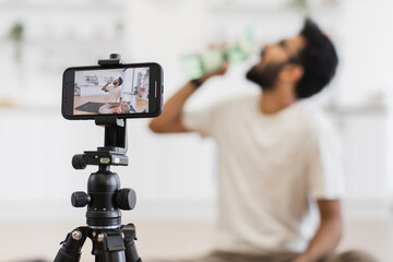 Adult man creating content for video blog discussing fitness and importance of hydration