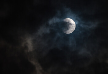 September's full moon, known as the Blood Moon, rises in the sky in Tehatta. As the eclipse begins, a wall of clouds rolls in and obscures the moon, creating various textures in the sky.