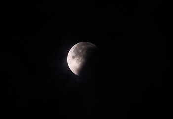 September's full moon, known as the Blood Moon, rises in the sky in Tehatta. As the eclipse begins, a wall of clouds rolls in and obscures the moon, creating various textures in the sky.
