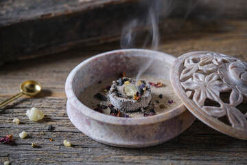 Incense and herbs burning in a traditional soapstone bowl, close-up