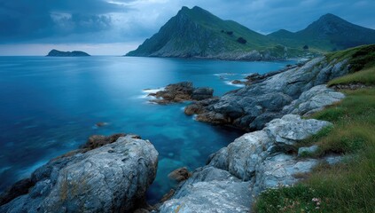 Fototapeta premium Coastal landscape at twilight. Dark, moody mountains meet turquoise water. Rocky shore
