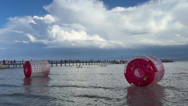 Fun water sports with inflatable balls at a beach pier during a sunny day with clouds