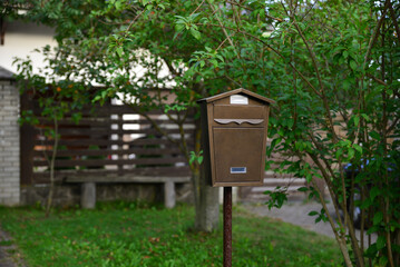 Brown mailbox on a pole on the street near the house