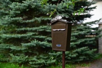 Brown mailbox on a pole on the street near the house