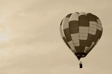 Fototapeta premium A vintage style image depicts a silhouette of a hot air balloon flying alone.