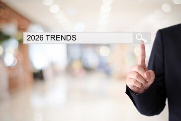 Man hand touching 2026 trends, business strategy, on search bar over blur office background, success in business concept