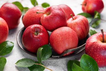 Fresh red apples resting on rustic metal plate with green leaves