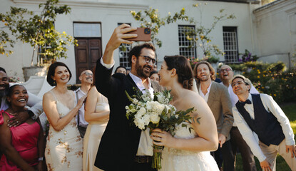 Bride and groom taking a selfie with joyful friends at an outdoor micro wedding