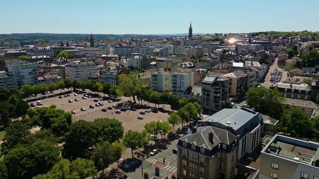 Forward drone fly over the Limoges cityscape with church spire and old buildings under summer sky, neighborhood station, Haute-Vienne, France.