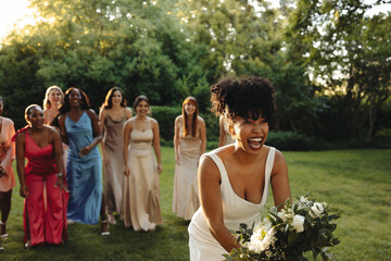 Bride tossing her bouquet surrounded by joyous bridesmaids in a lush garden