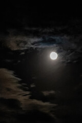 Bright full moon illuminating dark, swirling clouds in a night sky, creating a captivating and mysterious atmosphere filled with drama and intrigue, perfect for evoking a spooky halloween vibe