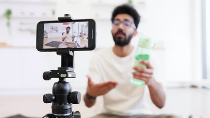 Young man recording health video blog discussing fitness, water consumption, proper hydration, lifestyle tips. Engages digital audience by sharing techniques for better sports practices.
