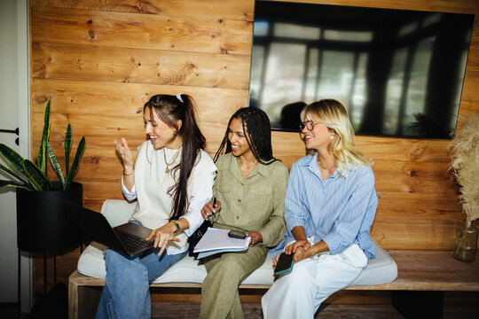 Influencer friends sharing ideas on laptop indoors