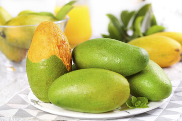Fresh Green Mangoes with Coconut and Tropical Fruits on White Plate