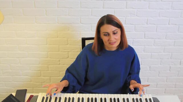 Beauty woman playing a digital piano synthesizer in a living room, smiling and enjoying the music lesson or practice session.