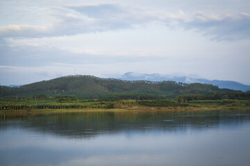 Clear lake water reflects mountains and forest landscape on peaceful windy day