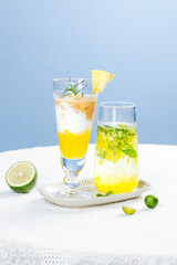 Tropical Layered Cocktails with Pineapple and Lime Garnish on Blue Background