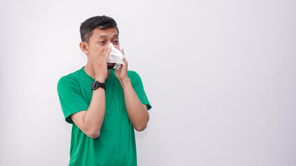Asian man cover his nose and mouth with tissue when sneezing isolate on white background. wearing...