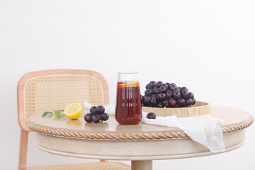 Fresh Grape Juice with Dark Grapes and Lemon on Wooden Table in Bright Summer Light