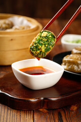 Asian Dumpling with Chives and Eggs Dipped in Soy Sauce Using Red Chopsticks