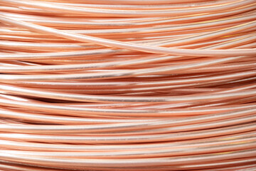 Close-up of coiled copper wires, showcasing their shiny surface and intricate overlapping pattern,...