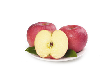 Fresh Red Apples Arranged on White Plate with Cut Half Showing Interior on White Background