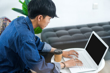Indonesian Man Focused On Work While Using Laptop And Drinking Coffee Representing Remote Work