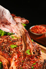 Slow-cooked lamb ribs being pulled apart showing tender meat with crispy spiced crust and fresh herb garnish