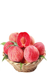 Fresh Ripe Peaches in Wicker Basket with Cut Half Showing Red Flesh on White Background