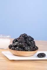 Air-Dried Xinjiang Prunes in Wooden Bowl - Healthy Dried Fruit Snack on White Plate