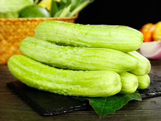 Fresh Green Cucumbers on Slate Board with Wicker Basket Background