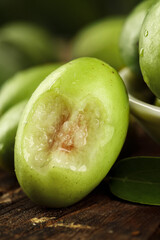 Fresh Green Chaoshan Olives Cut in Half on Wooden Surface - Traditional Asian Fruit