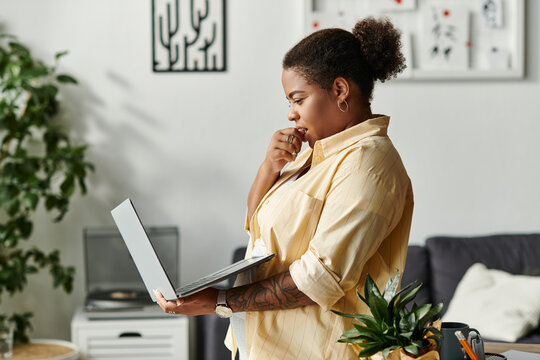 Focused african american woman working from home on her laptop in cozy apartment space