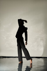 Elegant young man poses gracefully on reflective surface in minimalist setting