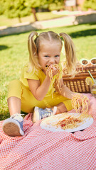 Little girl with pigtails playfully eating spaghetti with hands. Concept of sensory play, emotional...