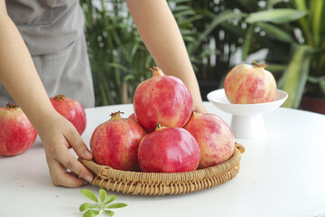 Fresh Pomegranates in Wicker Basket - Healthy Organic Fruit Display with Woman's Hands