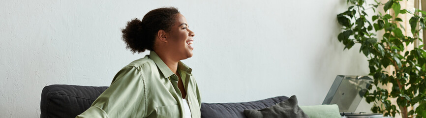 Smiling Black woman relaxes in her stylish apartment, enjoying her home time