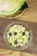 Fresh Cabbage Salad with Blueberries and Radishes in Glass Bowl on Wooden Table