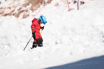 Child skier learning to ski on snowy slope in winter mountain resort