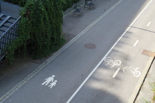 Piste cyclable et voie pi&eacute;tonne dessin&eacute;s sur le sol d'une route goudronn&eacute;e.